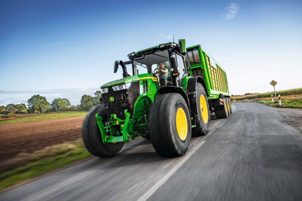 The model year 2024 John Deere 7R, driving on a road.